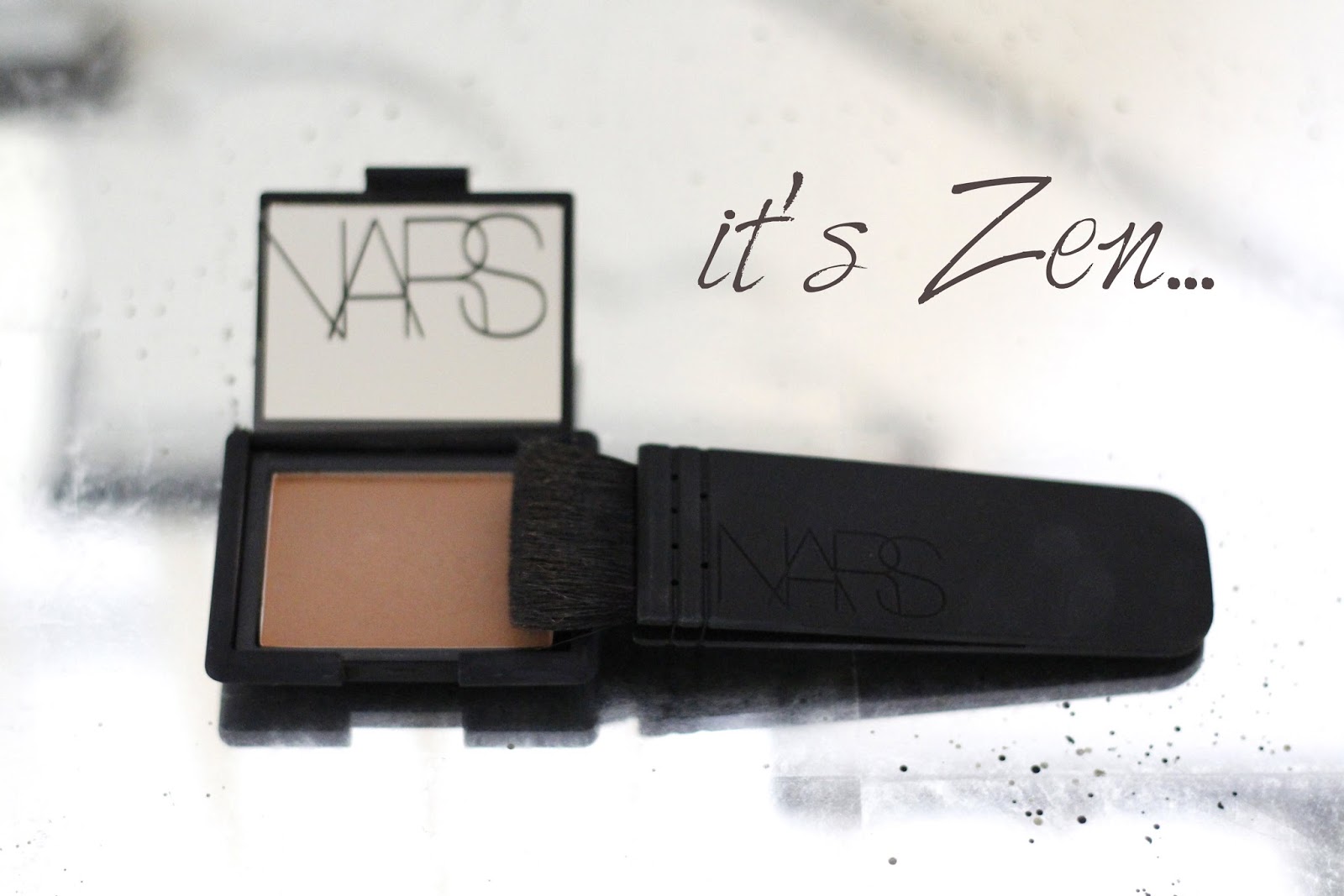 close-up of NARS blush in 'Zen' and NARS Artisan Kabuki Contour brush