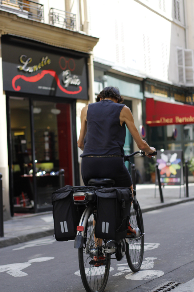 streetstyle - woman on bike riding through city street in Paris